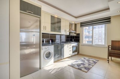 Spotless Duplex Apartment For Sale in Mahmutlar, Alanya - A large modern kitchen with built-in white goods